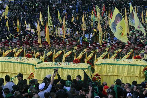 FILE - In this Tuesday, Oct. 27, 2015 file photo, relatives and comrades pray as they surround the Hezbollah flag-draped coffins of Shiite fighters who were killed in Syria, during a rally to mark the 13th day of the Shiite mourning period of Muharram, in Nabatiyeh, Lebanon. At tightly guarded facilities in south Lebanon, men as young as 17 undergo intensive training on how to use automatic rifles and heavy machine guns before being shipped off to Syria to fight alongside President Bashar Assad's forces. The training is part of a massive Hezbollah recruitment effort to make up for its human losses in Syria's war, now approaching the death toll incurred by the group during 18 years of fighting Israeli occupation.(AP Photo/Mohammed Zaatari, File)