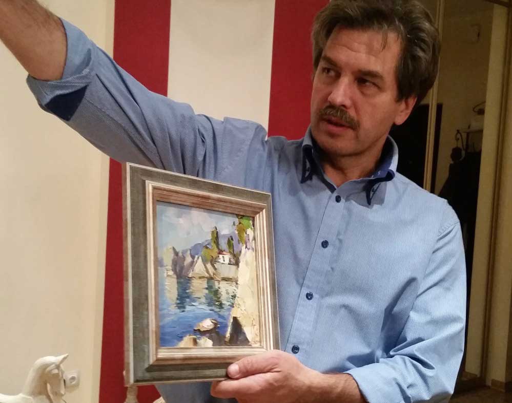 Nikolay in his St. Petersburg home with a painting of Chekhov's dacha in Ukraine