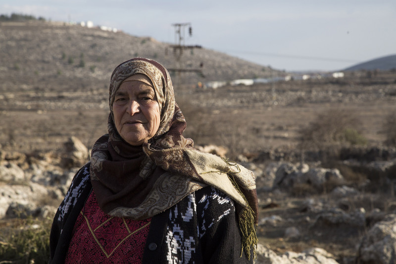 Maryam Hamad, from the West Bank village of Silwad, is pictured with the Israeli Ofra settlement in the background. She is one of the landowners on whose land the nearby Amona outpost was built. According to an Israeli high court decision, the settlers must evacuate this month. Photo/Keren Manor/ ActiveStills