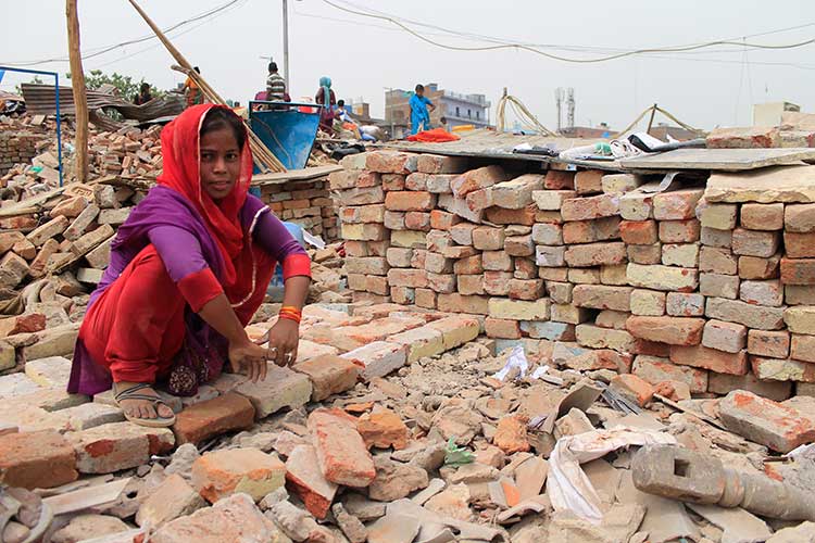 A young girl collets the belongings from under the debris after her house was demolished on July 5, 2017