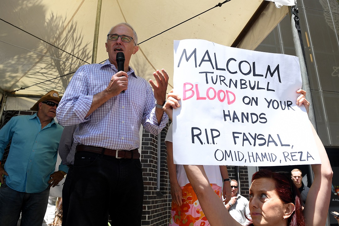 A protester holds a placard as Australian Prime Minister Malcolm Turnbull delivers his Christmas message as he and wife Lucy attend the Wayside Chapel Christmas Day service, in Sydney, Sunday, Dec. 25, 2016. (AAP Image/Dan Himbrechts) NO ARCHIVING