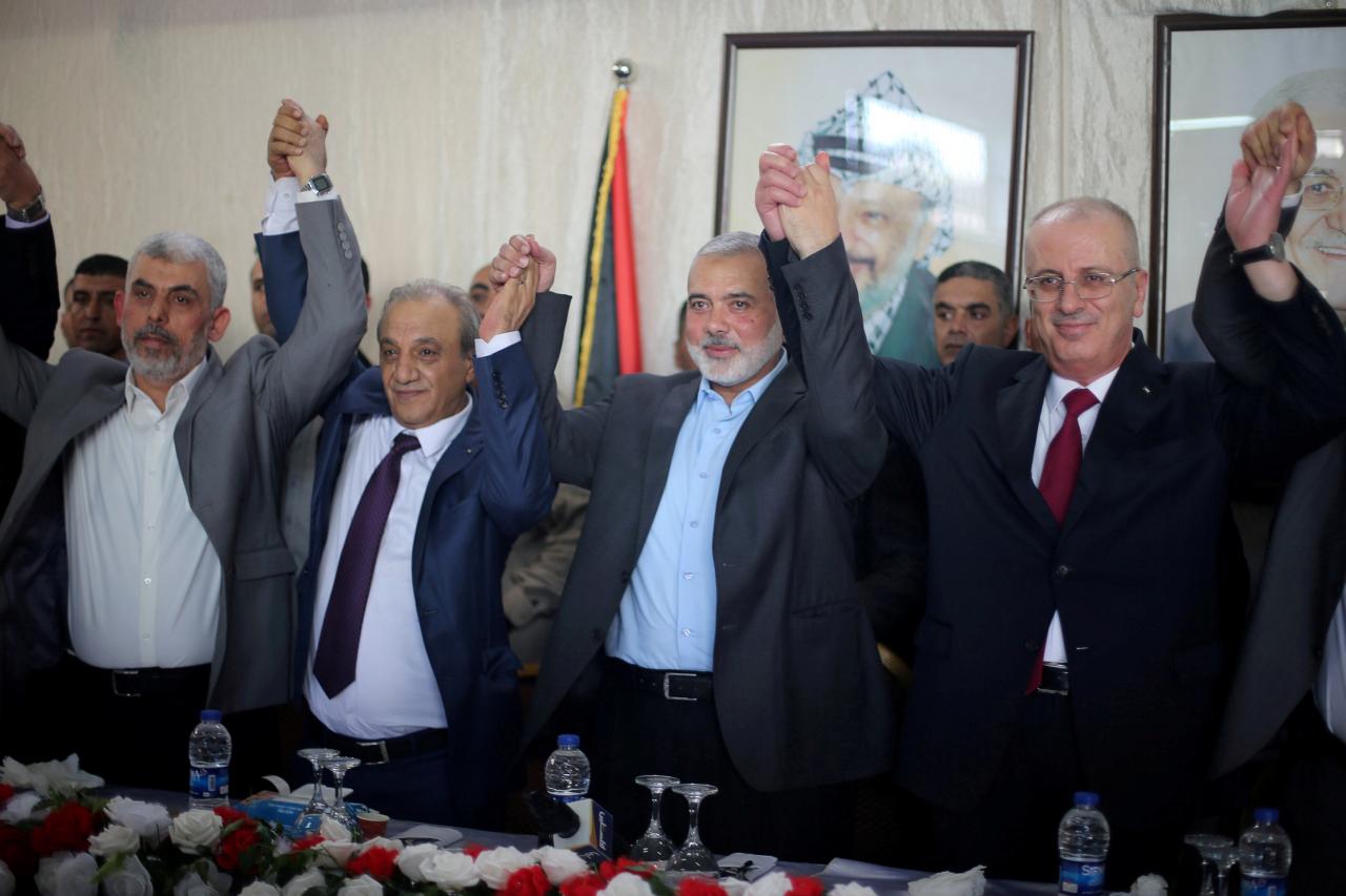 FILE PHOTO: Palestinian Prime Minister Rami Hamdallah (R) and Hamas Chief Ismail Haniyeh hold hands in Gaza City October 2, 2017. REUTERS/Ibraheem Abu Mustafa/File Photo