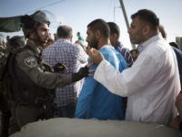 Israeli border police push Palestinian men as they try to cross through the Qalandiya checkpoint, between the cities of Jerusalem and Ramallah in the occupied West Bank, on 11 July. 
  (Oren Ziv /  ActiveStills)