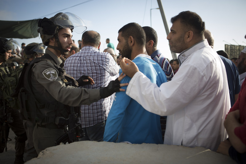 Israeli border police push Palestinian men as they try to cross through the Qalandiya checkpoint, between the cities of Jerusalem and Ramallah in the occupied West Bank, on 11 July. (Oren Ziv / ActiveStills) 