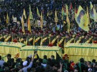FILE - In this Tuesday, Oct. 27, 2015 file photo, relatives and comrades pray as they surround the Hezbollah flag-draped coffins of Shiite fighters who were killed in Syria, during a rally to mark the 13th day of the Shiite mourning period of Muharram, in Nabatiyeh, Lebanon. At tightly guarded facilities in south Lebanon, men as young as 17 undergo intensive training on how to use automatic rifles and heavy machine guns before being shipped off to Syria to fight alongside President Bashar Assad's forces. The training is part of a massive Hezbollah recruitment effort to make up for its human losses in Syria's war, now approaching the death toll incurred by the group during 18 years of fighting Israeli occupation.(AP Photo/Mohammed Zaatari, File)