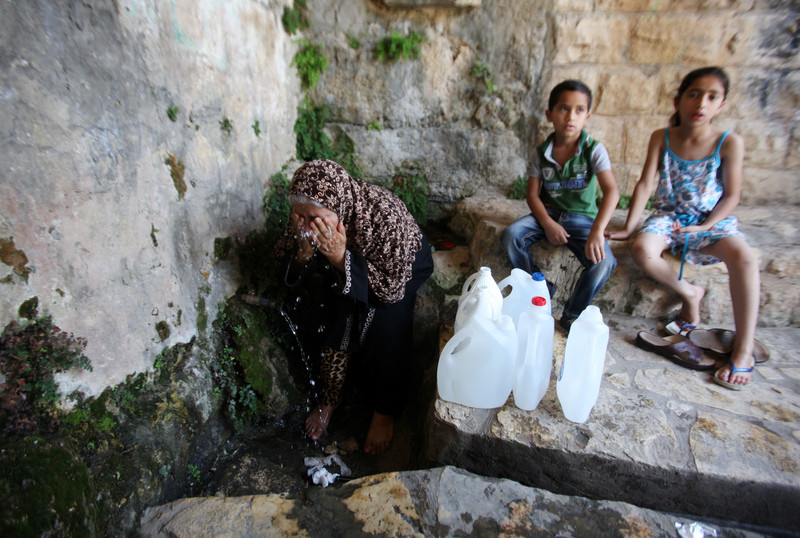 A Palestinian woman fills a jerrican with spring water on June 27, 2016 in Salfit, north of Ramallah, where some of the West Bank village's inhabitants have been without water for days. Tens of thousands of Palestinians in the Israeli-occupied West Bank have gone without water in recent weeks, victims of the latest dispute between Israeli and Palestinian officials over the region's most valuable resource. Photo by Nedal Eshtayah
