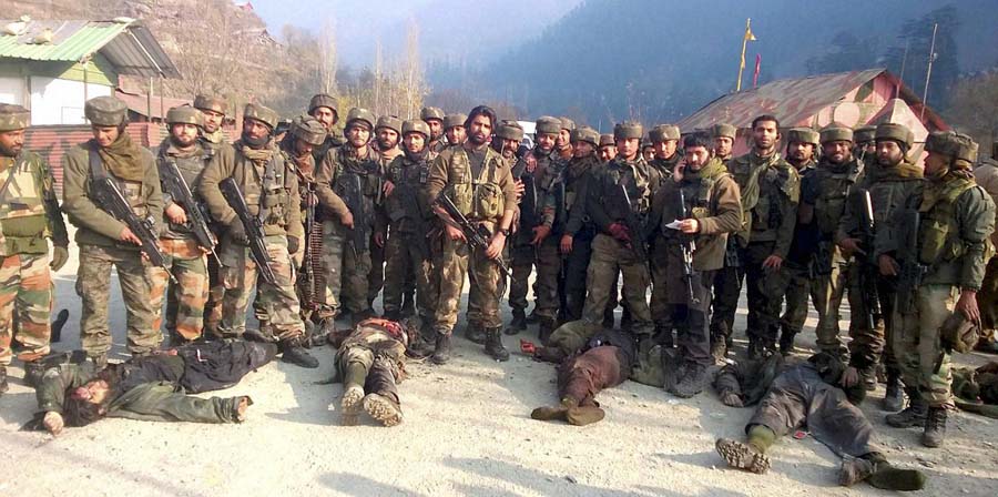 Uri: Army personnel stand near the dead bodies of militants who attacked Mohura army camp, in Uri on Saturday. PTI Photo(