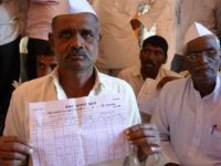 A farmer in Nagur holds up an extract of his loan account from the credit cooperative society; further interest of 2-4 per cent gets added at the level of the societies