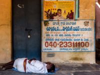 Writing on the wall: an out-of-work Dalit man rests outside the ration store in Bucharla. Ironically, a government helpline number for the jobless is painted on the wall 