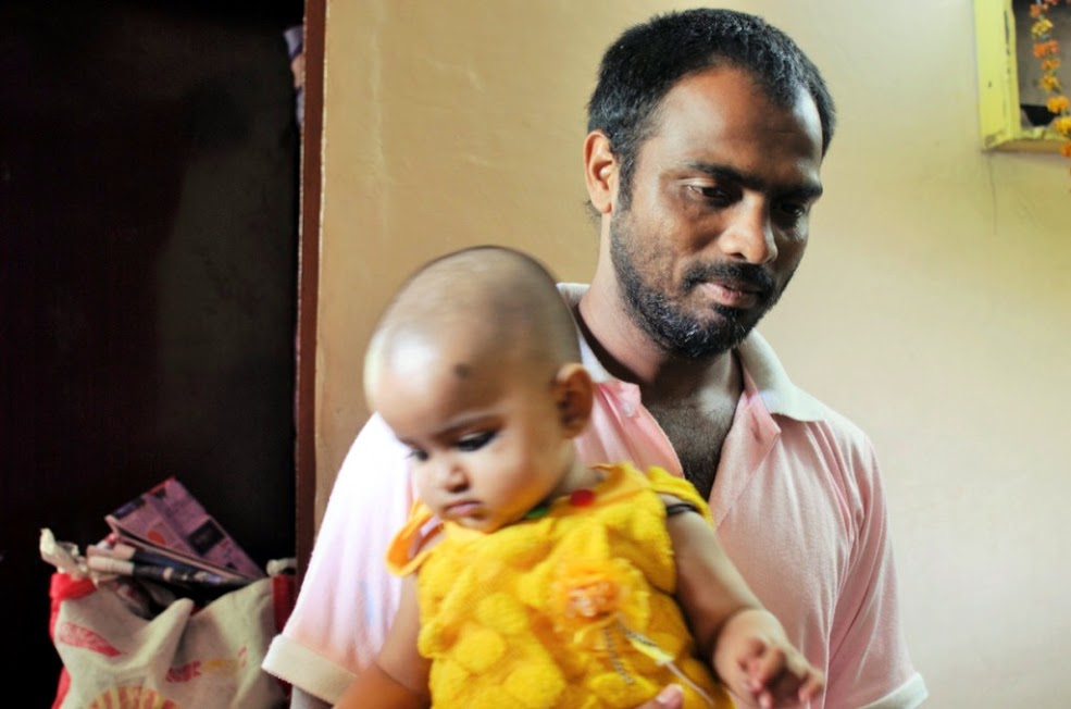 Ashwani, a washerman at his house next to the ghat, with his baby daughter.