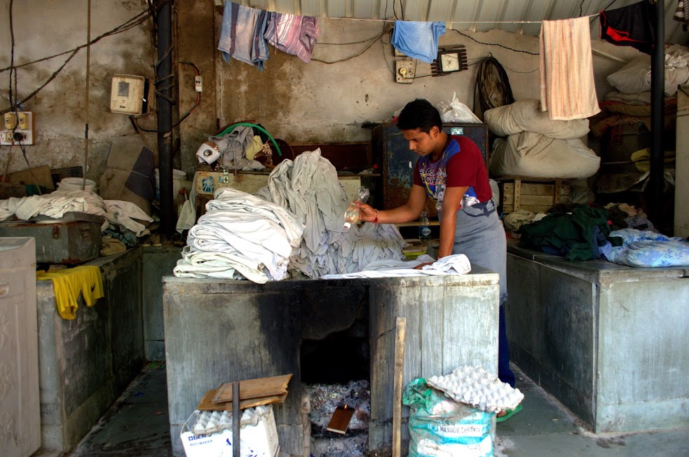 A washerman applies disinfectants to a bundle of clothes at the Devi Prasad Sadan Ghat.