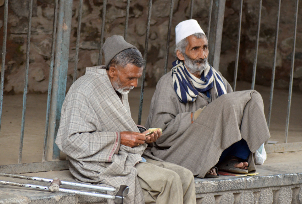Two elderly Kashmiri men sitting out in a pavement next to the mental hospital after collecting their anti-depressants.