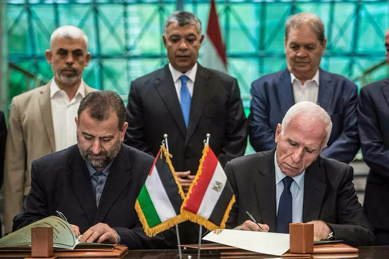 Hamas's new deputy leader Salah al-Aruri (seated L) and Fatah's Azzam al-Ahmad (seated R) sign a reconciliation deal in Cairo on October 12, 2017, as the two rival Palestinian movements ended their decade-long split following negotiations overseen by Egypt. Under the agreement, the West Bank-based Palestinian Authority is to resume full control of the Hamas-controlled Gaza Strip by December 1, according to a statement from Egypt's government. . Photo by STR