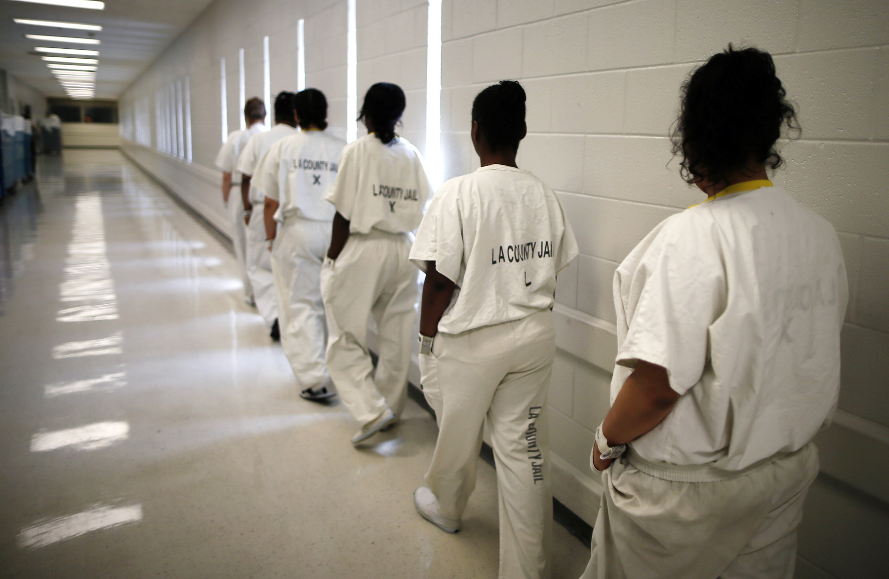 Women walk along a corridor at the Los Angeles County women's jail in Lynwood, California April 26, 2013. The Second Chance Women's Re-entry Court is one of the first in the U.S. to focus on women, and offers a cost-saving alternative to prison for women who plead guilty to non-violent crimes and volunteer for treatment. Of the 297 women who have been through the court since 2007, 100 have graduated, and only 35 have been returned to state prison. REUTERS/Lucy Nicholson (UNITED STATES - Tags: CRIME LAW) - RTXZ1G4