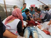 Palestinian medics treat a wounded protester after he was shot by Israeli soldiers during Great March of Return protests in Khan Younis, southern Gaza Strip, 10 August. Ashraf Amra APA images