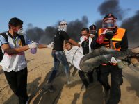 Paramedics carry an injured protester during Great March of Return demonstrations east of Khan Younis, southern Gaza Strip, on 28 September. Ashraf Amra  - APA images