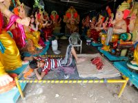 A vendor selling idols of Hindu god Ganesh, the deity of prosperity, rests as he waits for customers at a roadside workshop in Ahmedabad, India, August 29, 2016. (Photo by Amit Dave/Reuters)