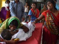 An Indian child arrives in a hospital due to Acute Encephalitis Syndrome (AES) as family members react in Muzaffarpur on June 10, 2019. - At least 14 children have died due to Acute Encephalitis Syndrome (AES) while over a dozen are admitted in hospitals. (Photo by STR / AFP)