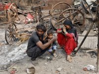 A woman sitting with her husband and their child reacts next to damaged property after their house was burnt by a mob on Tuesday in a riot affected area after clashes erupted between people demonstrating for and against a new citizenship law in New Delhi, India, February 28, 2020. REUTERS/Adnan Abidi - RC2L9F9XG1SM