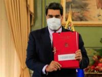 Venezuelan President Nicolas Maduro holds up a copy of his anti-blockade law.