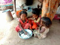 Gudiya (name changed) at her house, eating plain rice form a plate, sharing it with her sisters- Photo Courtsey - Sachin Kumar Jain