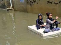 Girls use a temporary raft across a flooded street in a residential area after heavy monsoon rains in Karachi on July 26, 2022. A weather emergency was declared in Karachi as heavier-than-usual monsoon rains continue to lash Pakistan's biggest city, flooding homes and making streets impassable. (Photo: Rizwan Tabassum/AFP via Getty Images)