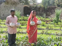Sarita and Rambohar with their preserved seeds, standing in their garden