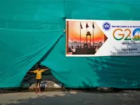 A boy pulls up plastic sheeting placed to screen a slum area alongside a road ahead of the G20 summit in New Delhi. Photograph: Amit Dave/Reuters