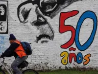 A man pedals his bicycle past a mural marking the 50th anniversary of the country's military coup, with a reminder of those disappeared during the Augusto Pinochet regime and an image depicting the deposed President Salvador Allende, in Santiago, Chile, Friday, September 8, 2023
